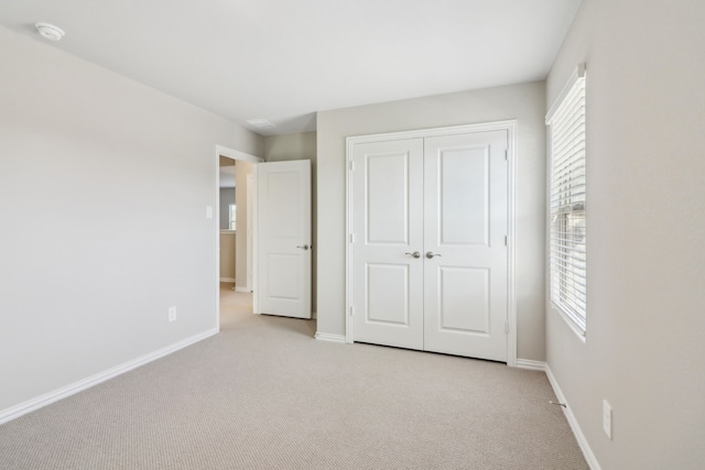 unfurnished bedroom with light colored carpet and a closet