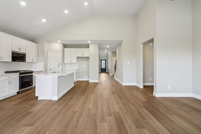 kitchen featuring white cabinetry, sink, stainless steel appliances, and a center island with sink