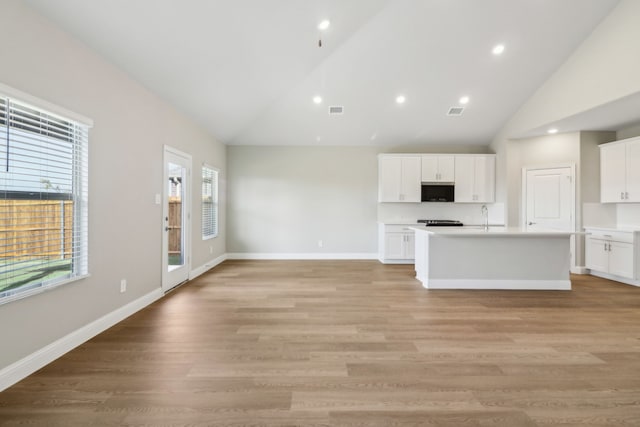 kitchen with white cabinetry, light hardwood / wood-style floors, a center island with sink, and sink