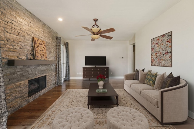 living room with hardwood / wood-style floors, a stone fireplace, and ceiling fan