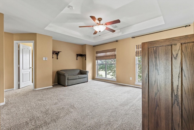 unfurnished room featuring a tray ceiling, ceiling fan, and carpet floors