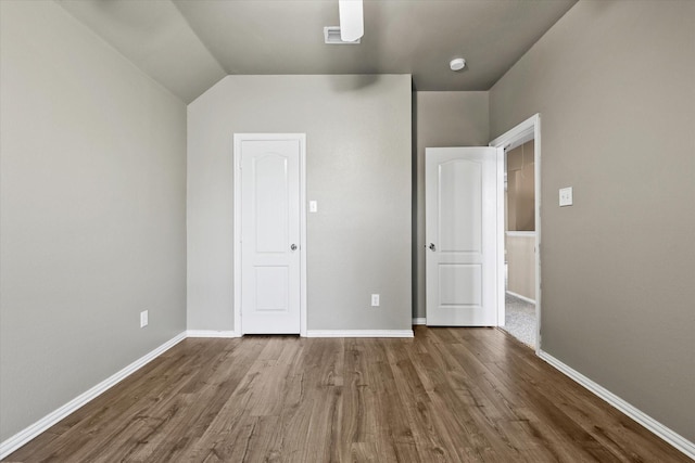 unfurnished bedroom featuring hardwood / wood-style floors and lofted ceiling