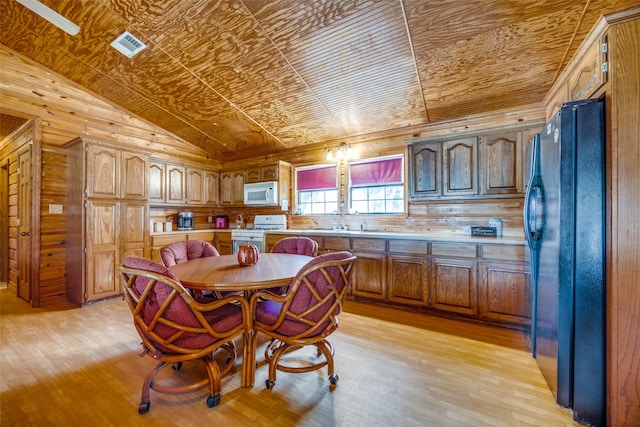 dining space with wood walls, light hardwood / wood-style flooring, and vaulted ceiling