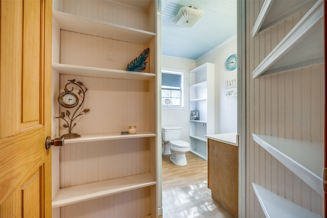 bathroom with crown molding, wood walls, hardwood / wood-style flooring, and toilet