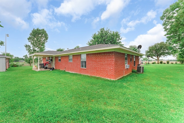 back of property with cooling unit, central AC, and a yard