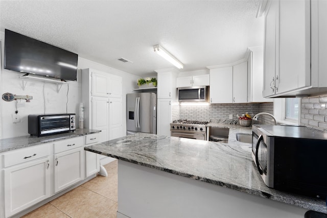 kitchen featuring stone counters, white cabinetry, light tile patterned floors, and appliances with stainless steel finishes