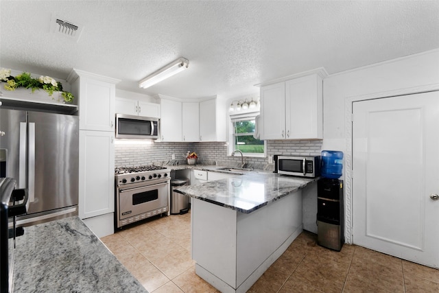 kitchen with white cabinetry, sink, kitchen peninsula, appliances with stainless steel finishes, and light stone countertops