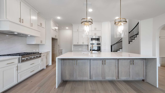 kitchen featuring visible vents, arched walkways, white cabinets, appliances with stainless steel finishes, and light wood-type flooring