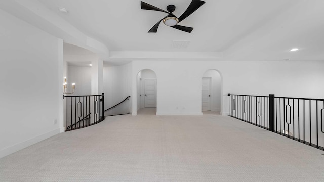 empty room featuring ceiling fan with notable chandelier, baseboards, arched walkways, and carpet floors