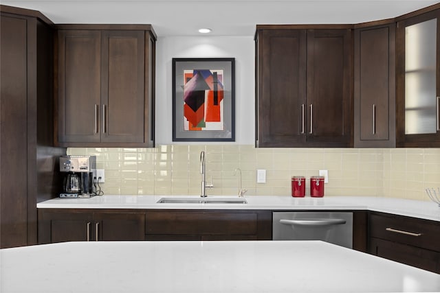 kitchen featuring dishwasher, dark brown cabinetry, sink, and tasteful backsplash