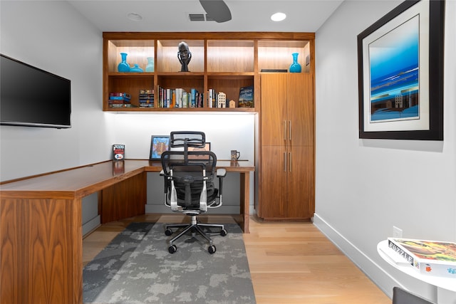 office with built in desk and light hardwood / wood-style flooring