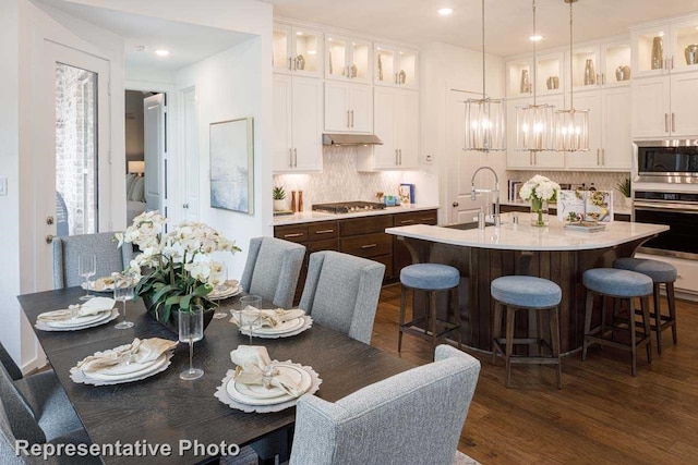 kitchen featuring stainless steel appliances, a center island with sink, and white cabinetry