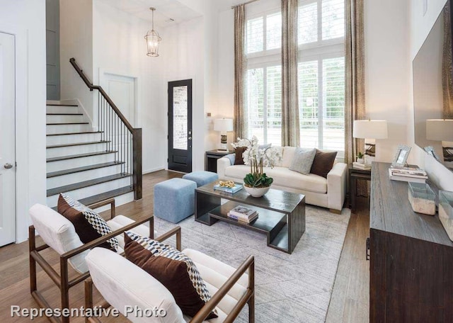 living room featuring a high ceiling, a chandelier, and light hardwood / wood-style flooring