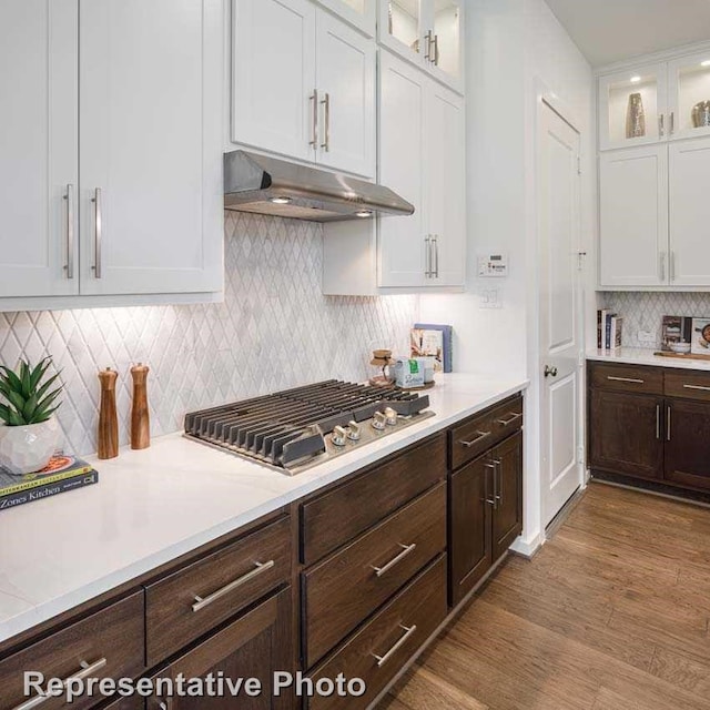 kitchen featuring tasteful backsplash, light wood-type flooring, stainless steel gas stovetop, and white cabinets