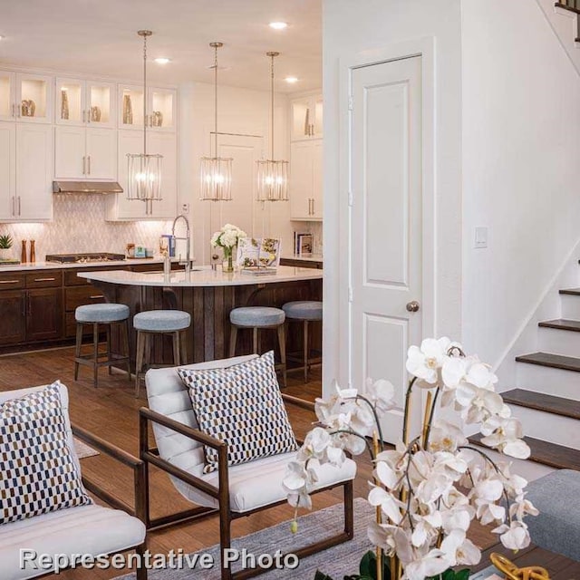 kitchen featuring a center island with sink, dark hardwood / wood-style floors, backsplash, hanging light fixtures, and stainless steel gas stovetop