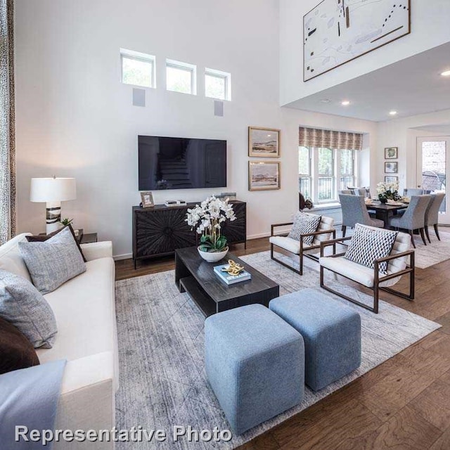 living room with hardwood / wood-style floors, plenty of natural light, and a high ceiling