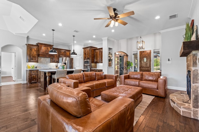 living room with a fireplace, crown molding, dark hardwood / wood-style flooring, and ceiling fan with notable chandelier