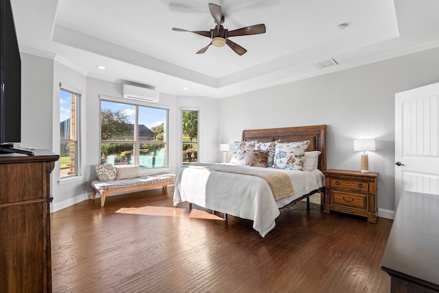 bedroom with a wall mounted air conditioner, dark hardwood / wood-style flooring, a tray ceiling, and ceiling fan