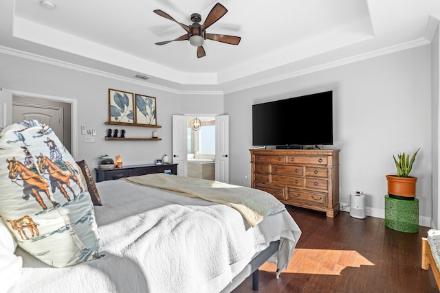 bedroom with a tray ceiling, connected bathroom, dark hardwood / wood-style flooring, and ceiling fan with notable chandelier