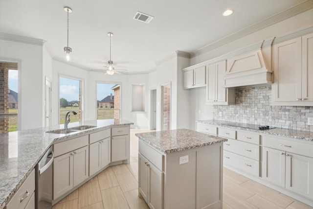 kitchen with a kitchen island with sink, sink, crown molding, and decorative light fixtures