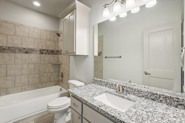 full bathroom featuring hardwood / wood-style floors, vanity, toilet, and tiled shower / bath