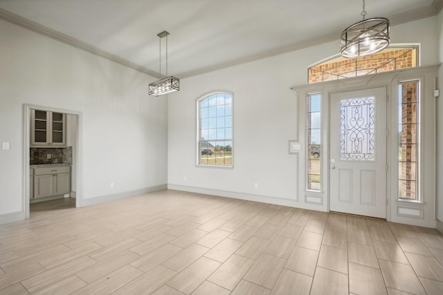 entrance foyer with a chandelier, crown molding, and light hardwood / wood-style floors