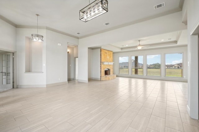 unfurnished living room with ceiling fan with notable chandelier, a raised ceiling, crown molding, light wood-type flooring, and a fireplace