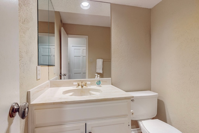 bathroom featuring vanity, toilet, and a textured ceiling