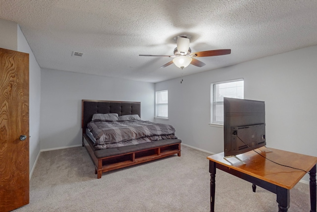 carpeted bedroom with ceiling fan and a textured ceiling