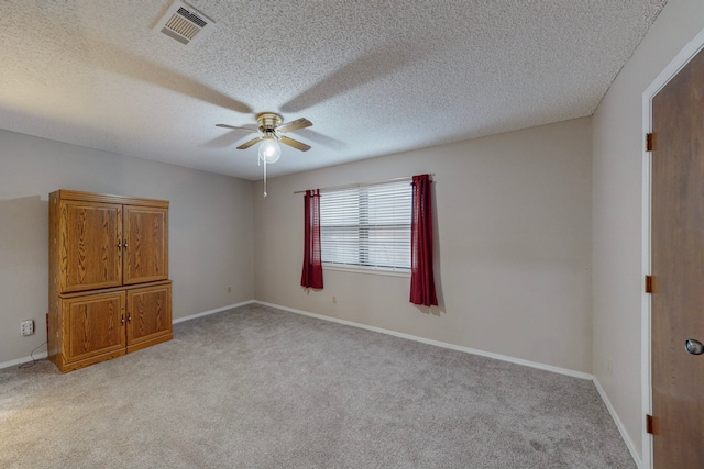 carpeted spare room featuring ceiling fan and a textured ceiling