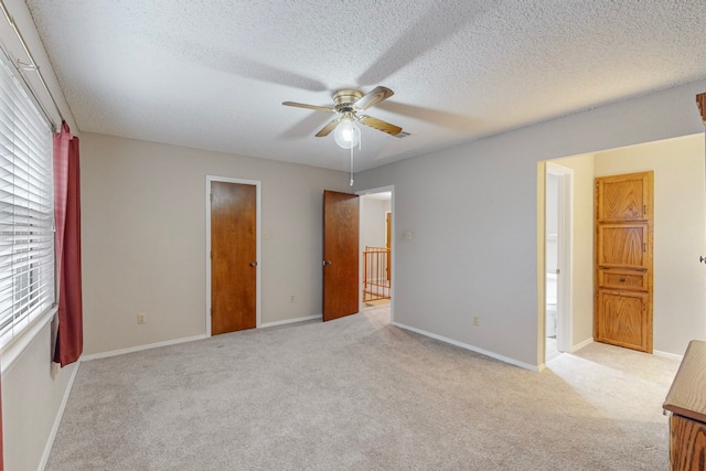 unfurnished bedroom with a textured ceiling, light carpet, and ceiling fan