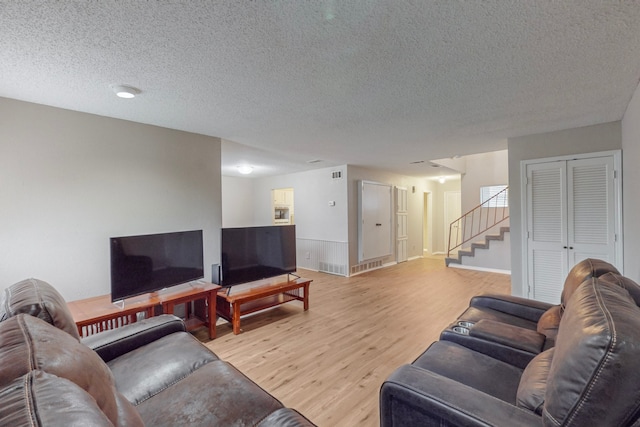 living room featuring light wood-type flooring and a textured ceiling