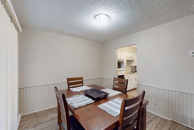 dining area featuring a textured ceiling and light wood-type flooring