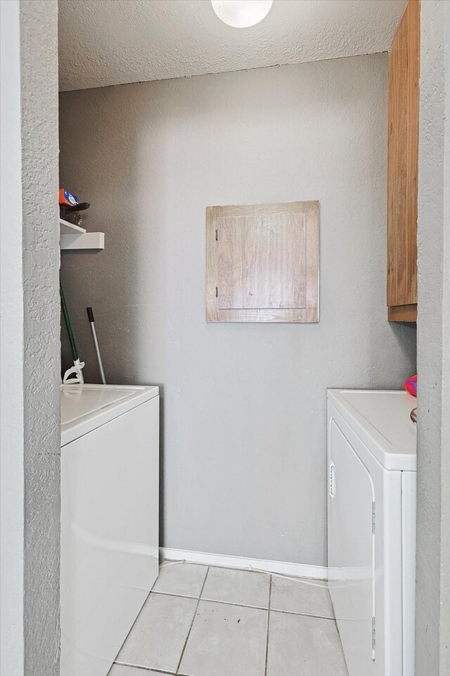 washroom featuring washing machine and clothes dryer, a textured ceiling, and light tile patterned floors