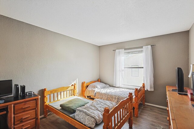 bedroom with dark hardwood / wood-style floors and a textured ceiling