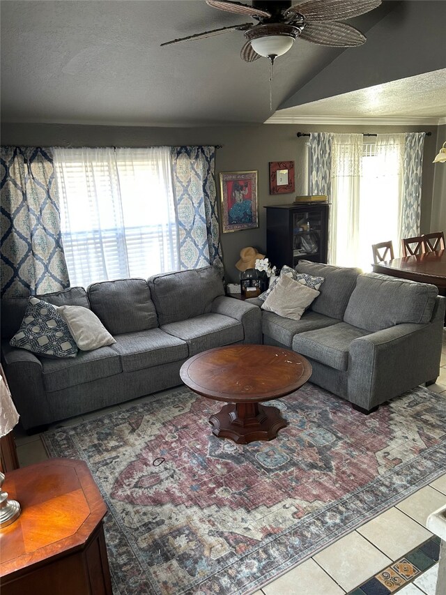 living room featuring crown molding, light tile patterned floors, ceiling fan with notable chandelier, and vaulted ceiling