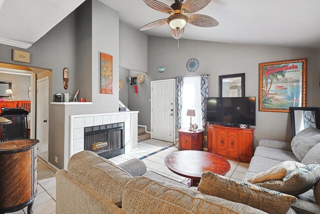 tiled living room with a tiled fireplace, vaulted ceiling, and ceiling fan