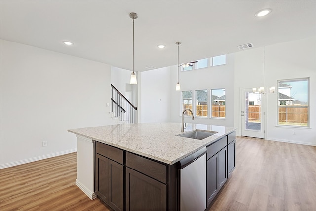 kitchen featuring sink, hanging light fixtures, stainless steel dishwasher, and light stone countertops