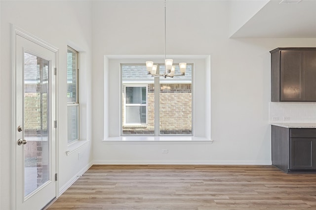 unfurnished dining area with light hardwood / wood-style floors and an inviting chandelier