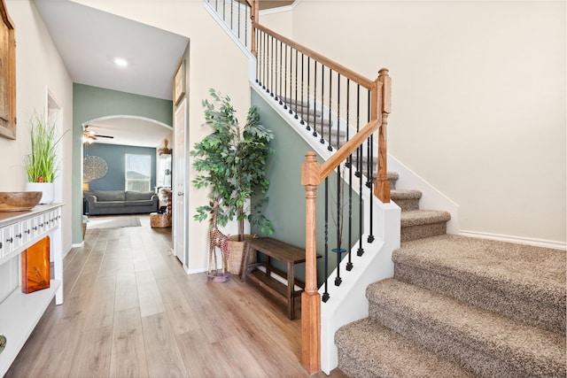 stairway with ceiling fan and hardwood / wood-style flooring