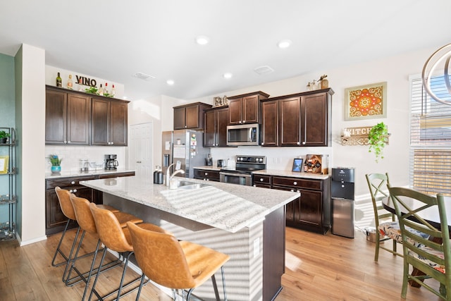 2816 Brosnan Rd, Waco, TX 76655 - kitchen with stainless steel appliances, light wood finished floors, dark brown cabinets, a breakfast bar area, and a sink