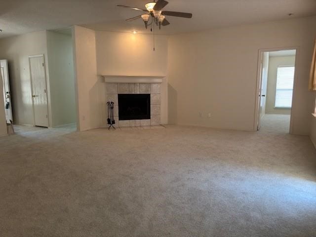 unfurnished living room with a fireplace, ceiling fan, and light colored carpet