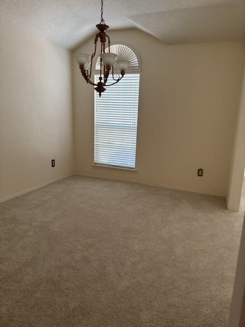 unfurnished room with a textured ceiling, carpet flooring, an inviting chandelier, and vaulted ceiling