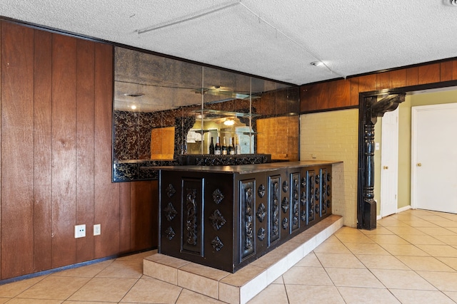 bar with wooden walls, a textured ceiling, and light tile patterned floors