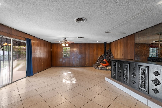 tiled spare room featuring ceiling fan, a textured ceiling, and wooden walls