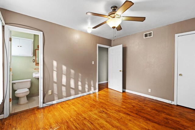 unfurnished bedroom with hardwood / wood-style flooring, ceiling fan, and ensuite bath