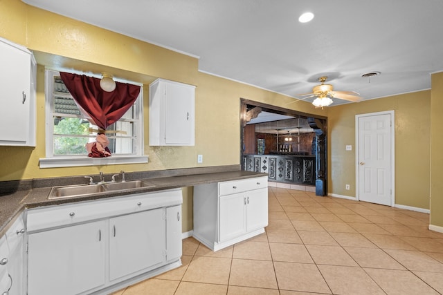 kitchen featuring light tile patterned floors, ceiling fan, white cabinetry, and sink