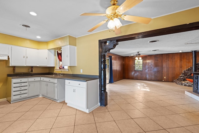 kitchen with wood walls, a textured ceiling, light tile patterned floors, and white cabinets