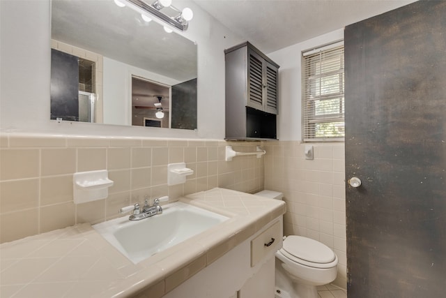 bathroom featuring toilet, tile walls, a textured ceiling, vanity, and ceiling fan