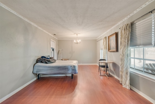 bedroom with hardwood / wood-style flooring, ornamental molding, a textured ceiling, and a notable chandelier